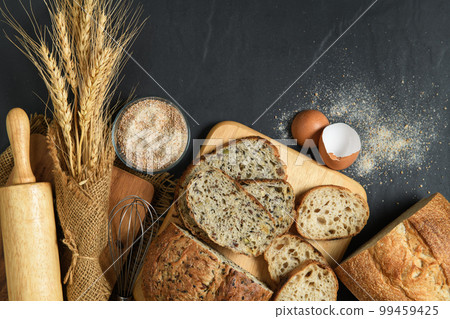 slide multi grain sourdough bread and sliced Baguette with Whole Wheat Flour on black stone background, 99459425