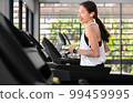 young happy asian woman athlete run on treadmill, running machine, in indoor gym fitness for health; 99459995