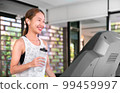 young happy asian woman athlete run on treadmill, running machine, in indoor gym fitness for health; 99459997