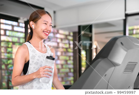 young happy asian woman athlete run on treadmill, running machine, in indoor gym fitness for health; 99459997