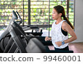 young happy asian woman athlete run on treadmill, running machine, in indoor gym fitness for health; 99460001
