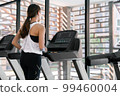 young happy asian woman athlete run on treadmill, running machine, in indoor gym fitness for health; 99460004