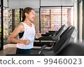 young happy asian woman athlete run on treadmill, running machine, in indoor gym fitness for health; 99460023