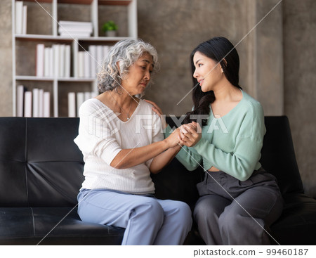 Daughter talking to sad mother holding hand comforting upset having problem 99460187