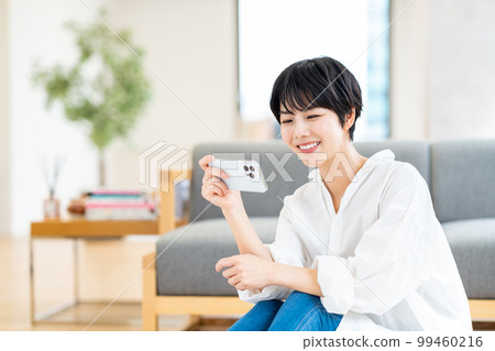 在客廳裡操作智能手機的女人 在客廳裡操作智能手機的女人 99460216