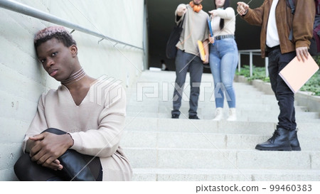 Classmates bullying sad black transgender man on stairs Classmates bullying sad black transgender man on stairs 99460383