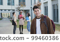 Cheerful young man with backpack on street 99460386