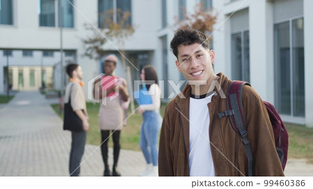 Cheerful young man with backpack on street Cheerful young man with backpack on street 99460386
