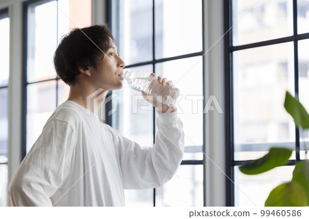 一個男人在窗邊喝瓶裝水 一個男人在窗邊喝瓶裝水 99460586