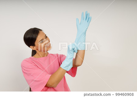 Cute young woman in homemade clothes and rubber gloves. Cleaning with rag. 99460908