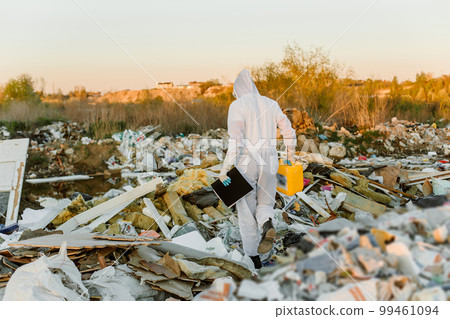Man in coveralls at trash pill. Doing research. Concept of ecology, environmental pollution. 99461094