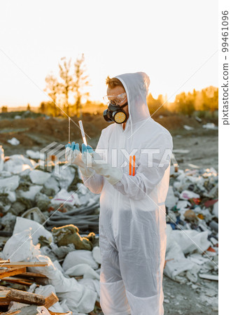Man in coveralls at trash pill. Doing research. Concept of ecology, environmental pollution. 99461096