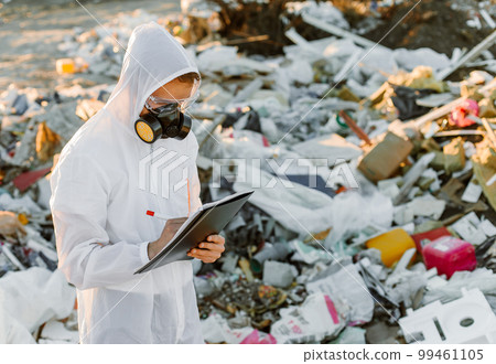 Man in coveralls at trash pill. Doing research. Concept of ecology, environmental pollution. 99461105