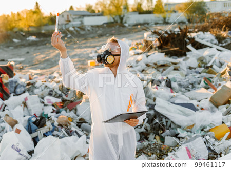 Man in coveralls at trash pill. Doing research. Concept of ecology, environmental pollution. Man in coveralls at trash pill. Doing research. Concept of ecology, environmental pollution. 99461117