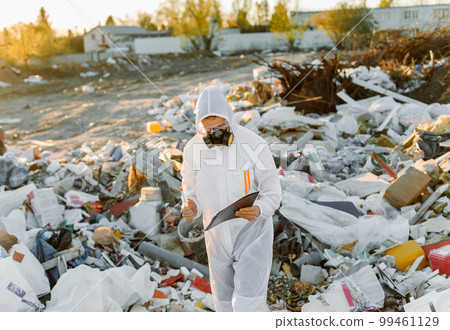 Man in coveralls at trash pill. Doing research. Concept of ecology, environmental pollution. Man in coveralls at trash pill. Doing research. Concept of ecology, environmental pollution. 99461129