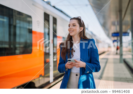 Woman holding mobile in a train station. Commuting to work. Public transport concept. 99461408