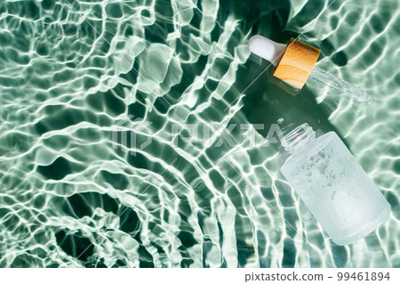 Facial pipette serum, essence cosmetic product in water drop splashing fresh transparent, flecks. Flat lay, top view. Facial pipette serum, essence cosmetic product in water drop splashing fresh transparent, flecks. Flat lay, top view. 99461894