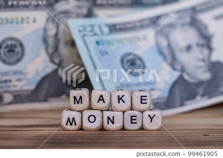 The words Make Money lined with letters on wooden cubes on the background of dollar bills. The words Make Money lined with letters on wooden cubes on the background of dollar bills. 99461905