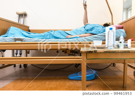 hospital bed with patient holding handle at home 99461953