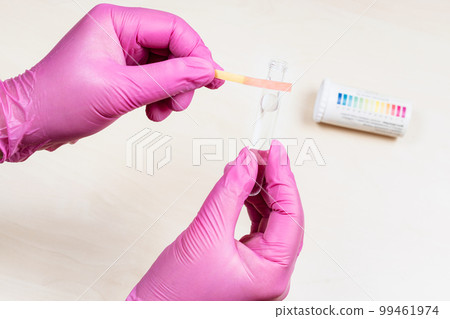 hands holding glass tube and pink litmus test 99461974