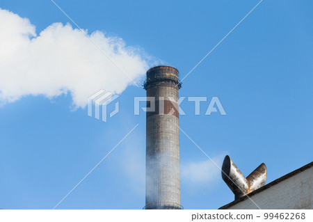 Pollution of the environment, atmosphere, air, environmental problems. Smoke is emitted from the industrial steam pipe of the plant opposite the cooling tower for cooling hot water in steam plants Pollution of the environment, atmosphere, air, environmental problems. Smoke is emitted from the industrial steam pipe of the plant opposite the cooling tower for cooling hot water in steam plants 99462268