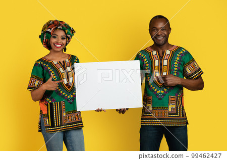 Emotional black couple in traditional costumes showing blank placard 99462427