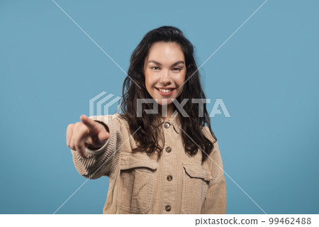 Cheerful millennial european woman student pointing finger at camera, isolated on blue background, studio 99462488