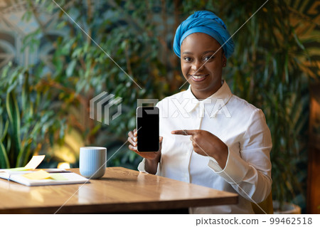 Cheerful african american woman showing cell phone with empty screen Cheerful african american woman showing cell phone with empty screen 99462518