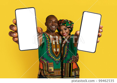 Beautiful loving black couple in traditional costumes showing cell phones Beautiful loving black couple in traditional costumes showing cell phones 99462535