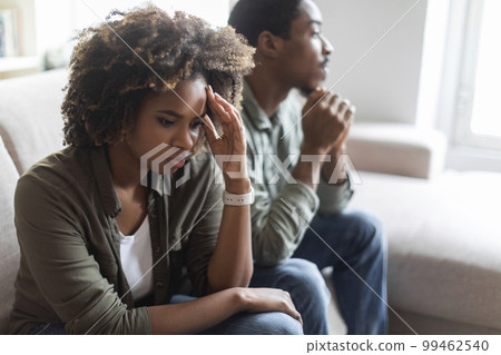 Unhappy black man and woman sittng on sofa at home Unhappy black man and woman sittng on sofa at home 99462540