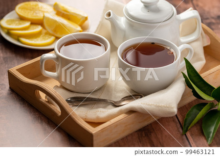 Two cups of black tea, tea pot and lemon slices. Tea time. Two cups of black tea, tea pot and lemon slices. Tea time. 99463121
