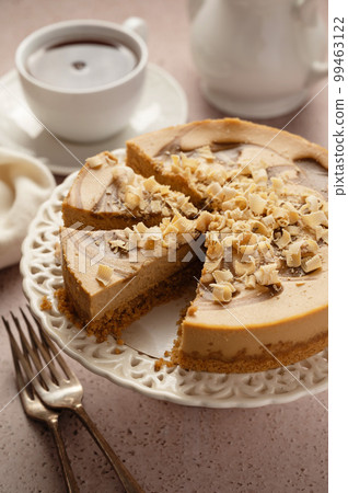Caramel cheesecake sliced and served with cup of tea 99463122