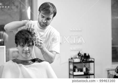 caucasian man getting haircut by professional male hairstylist caucasian man getting haircut by professional male hairstylist 99463160
