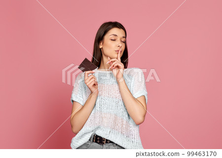 young woman in sweater holding chocolate bar 99463170