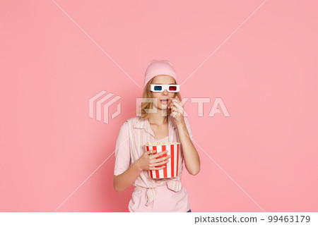 terrified girl watching horror movie , holding bucket of popcorn terrified girl watching horror movie , holding bucket of popcorn 99463179