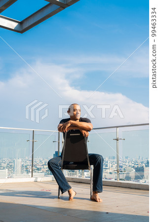 Portrait of handsome bald man sitting and thinking outdoors in city Portrait of handsome bald man sitting and thinking outdoors in city 99463334