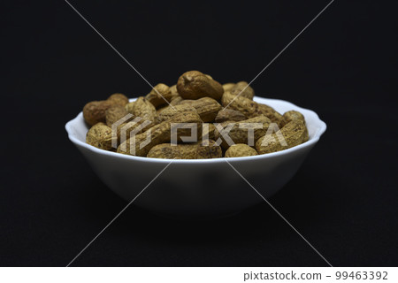 Groundnut. Unpeeled peanuts in a white plate. Peanuts in the peel. 99463392