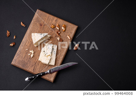 Delicious fresh cheese with blue mold dorblu on a wooden cutting board Delicious fresh cheese with blue mold dorblu on a wooden cutting board 99464008
