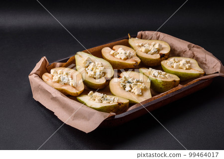 Delicious baked pear with dorblu cheese, walnut and honey on a textured concrete background Delicious baked pear with dorblu cheese, walnut and honey on a textured concrete background 99464017