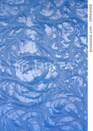 A beautiful drawing on a frozen window. Frosty pattern on the glass. Vertical. 99464068
