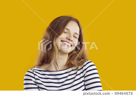 Portrait of happy young woman with closed eyes and dreamy and satisfied expression on her face. 99464878