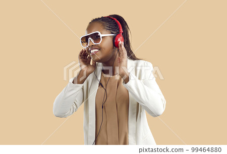 Studio portrait of happy black woman in headphones listening to her favorite playlist 99464880