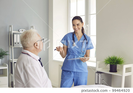 Smiling physician with clipboard interviewing senior patient during medical exam 99464920