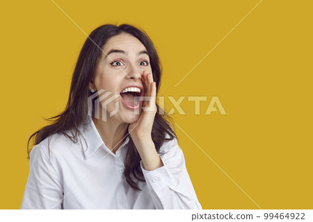 Joyful woman excitedly shouts something interesting to crowd, holding her hand to her mouth. 99464922
