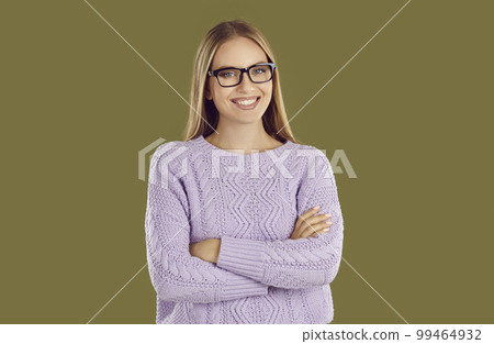 Young smiling girl in glasses and purple sweater is posing on khaki background looking at camera. Young smiling girl in glasses and purple sweater is posing on khaki background looking at camera. 99464932