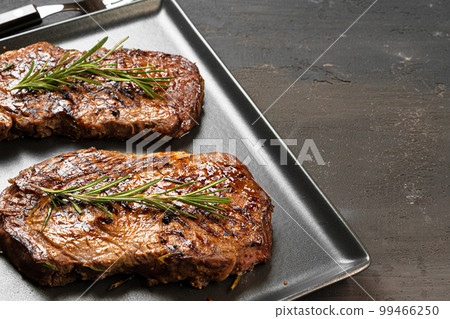 Grilled Beef steaks served with rosemary on metal tray 99466250