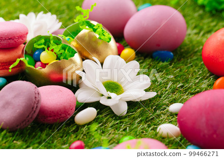 Close up photo of colored Easter eggs and candies on grass Close up photo of colored Easter eggs and candies on grass 99466271