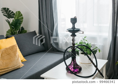 Hookah shisha with glass flask and metal bowl in room background. Traditional Eastern vacation for relaxation 99466341