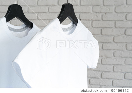 White t-shirt hanging on hanger against brick wall White t-shirt hanging on hanger against brick wall 99466522