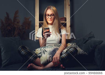Young woman using mobile phone. Sitting on the couch. Stay home concept during coronavirus covid-2019 99466666